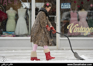 یک زن بوتیک دار در کانزاس آمریکا در حال برف روبی پیاده رو مقابل مغازه اش