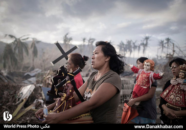 نجات یافتگان توفان هایان در مراسمی مذهبی در تولوسای فیلیپین. این عکس برنده جایزه اول در یکی از رشته های تک عکس خبری شده است.